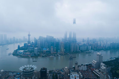 High angle view of city buildings against cloudy sky