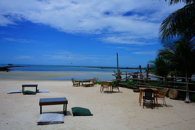 Chairs and tables on beach against sky