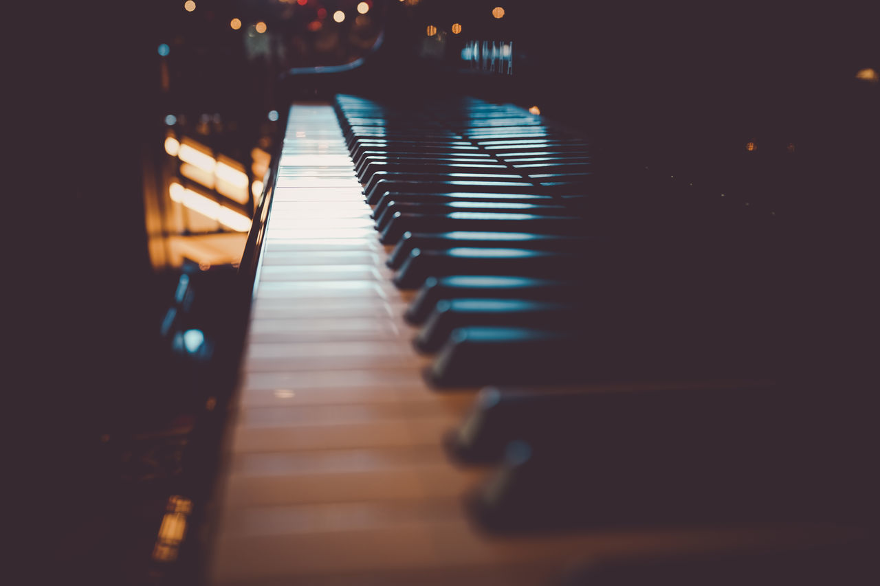 piano, musical equipment, musical instrument, music, arts culture and entertainment, no people, indoors, string instrument, light, in a row, illuminated, reflection, musical keyboard, night, piano key, darkness, selective focus, diminishing perspective