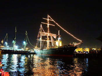 Illuminated ship by sea against sky at night