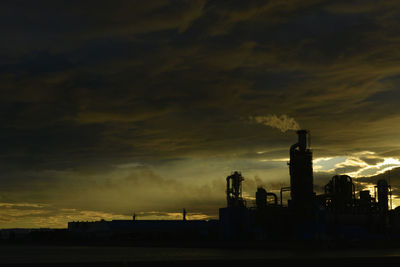 Smoke emitting from factory against sky during sunset