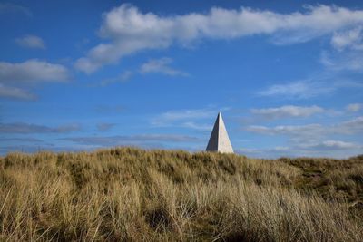 Monument in grassy field against sky