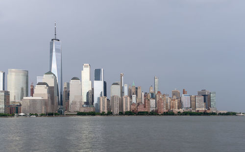 Sea by modern buildings against clear sky