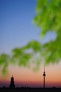 Illuminated fernsehturm against sky during sunset