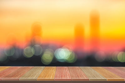 Defocused image of illuminated lights on table against sky during sunset