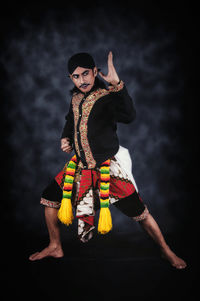 Portrait of man standing against black background