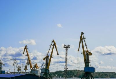 Cranes at harbor against sky