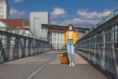 Full length of woman standing on railing against sky