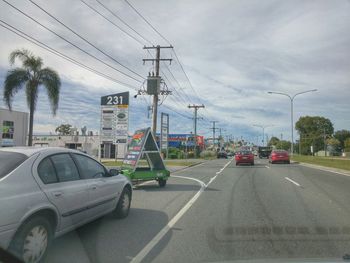 Cars on road against cloudy sky