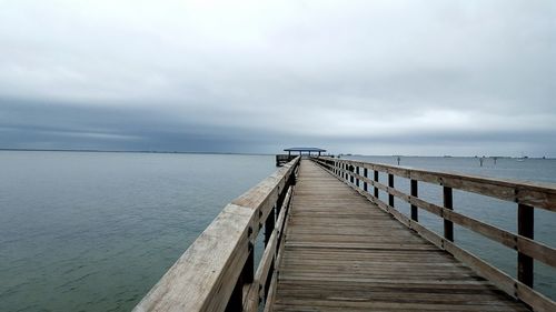 Pier amidst sea against cloudy sky