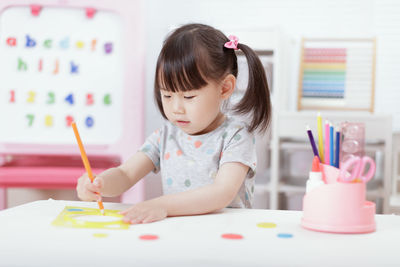 Young girl drawing on book at table