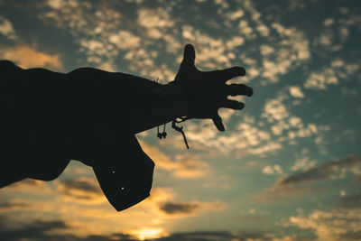 Low angle view of silhouette hand gesturing against sky during sunset