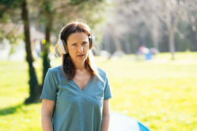 Portrait of beautiful woman wearing headphone while standing outdoors