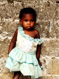 Portrait of cute girl standing against wall