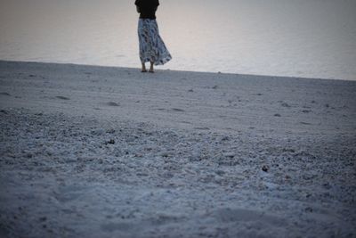 Low section of woman standing at beach