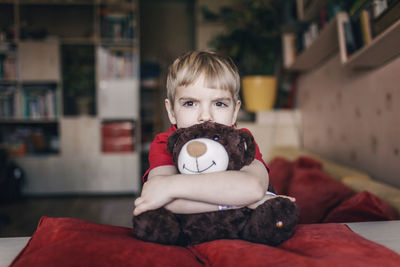 Portrait of boy with stuffed toy at home
