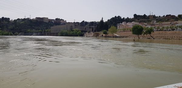 Scenic view of river by buildings against clear sky