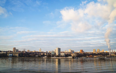 Buildings by river against sky