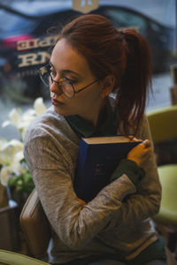 Young woman looking away while sitting on book