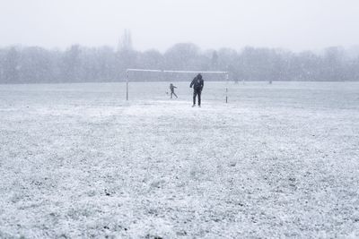 People playing sports on snowy field during winter