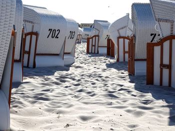 Hooded beach chairs on sand at beach against clear sky during sunny day
