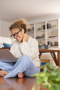 Young woman using mobile phone while sitting at home