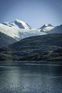 Scenic view of lake by snowcapped mountains against sky