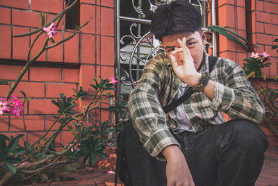 Young man looking away while sitting outdoors