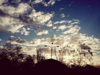 Silhouette of trees against cloudy sky