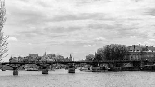 Bridge over river against cloudy sky