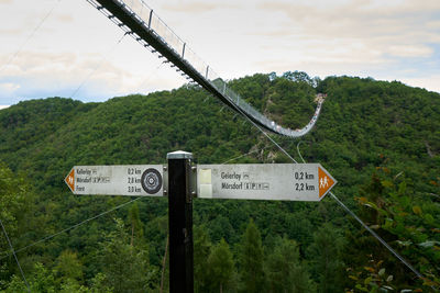 Information sign against trees on landscape against sky