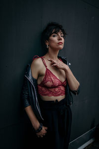 Portrait of seductive mid adult woman wearing bra against wall