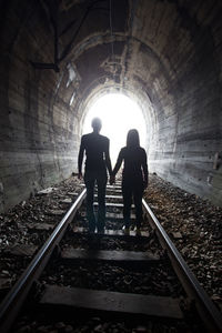 Rear view of men standing on railroad track
