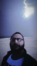 Portrait of mature man at beach against sky at night