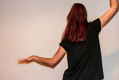 Rear view of woman standing against wall