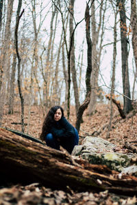 Portrait of young woman crouching in forest