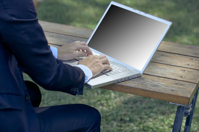 Man using mobile phone while sitting on wood