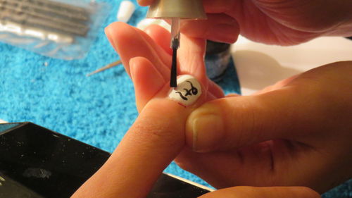 Close-up of woman applying nail polish on customer fingernails at beauty spa
