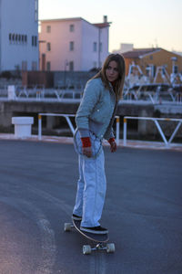 Woman skateboarding on road in city