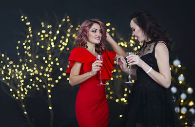 Beautiful women wearing gown holding drinks standing outdoors at night