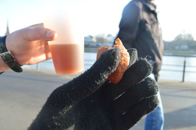 Close-up of woman holding camera against sky