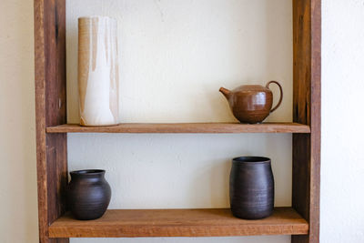 Close-up of objects on shelf against wall at home