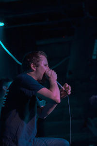 Side view of young man looking at camera