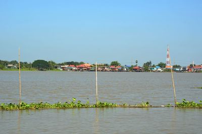 Scenic view of river by buildings against clear sky