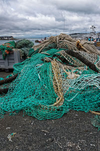 Fishing nets at harbor against cloudy sky