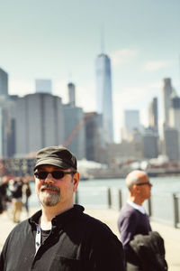 Portrait of man wearing sunglasses against buildings in city