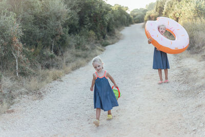 Full length of sisters walking on footpath amidst trees