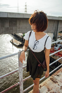 Rear view of man standing on railing against canal