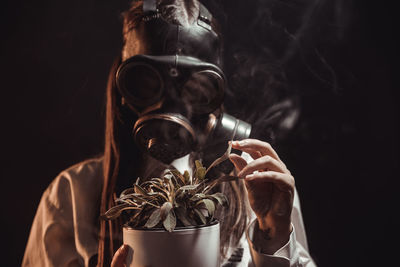 Close-up portrait of young man smoking against black background