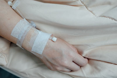 Midsection of woman with iv drip on bed